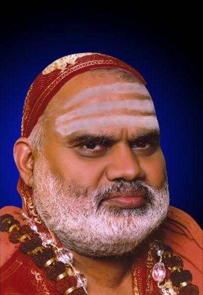 Close portrait of Jagadguru Sri Bharati Tirtha Mahaswamiji against a deep blue background, a saffron cloth over his head and vibhuti across his forehead